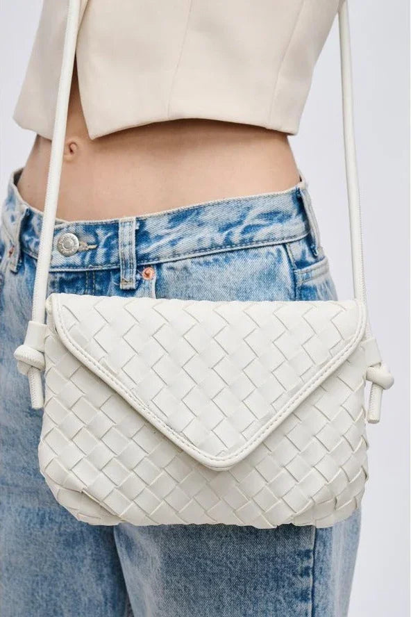 White woven crossbody bag with flap, worn over light jeans and cream crop top, Love Classic style