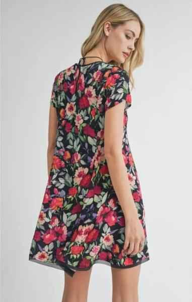 Woman wearing a short-sleeve floral dress from Love Classic, showcasing vibrant flower print