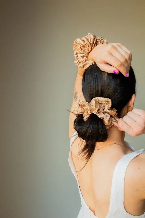 Woman with brown scrunchies in hair and on wrist, wearing white dress, Love Classic style