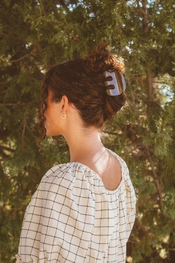 Woman in checkered blouse with hair clip and gold hoop earrings outdoors, Love Classic style