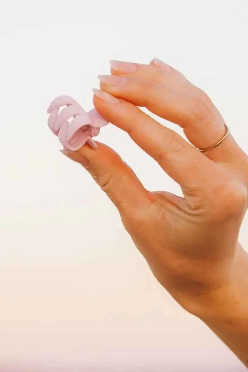 Hand holding a pink claw hair clip with natural nails, Love Classic style accessory