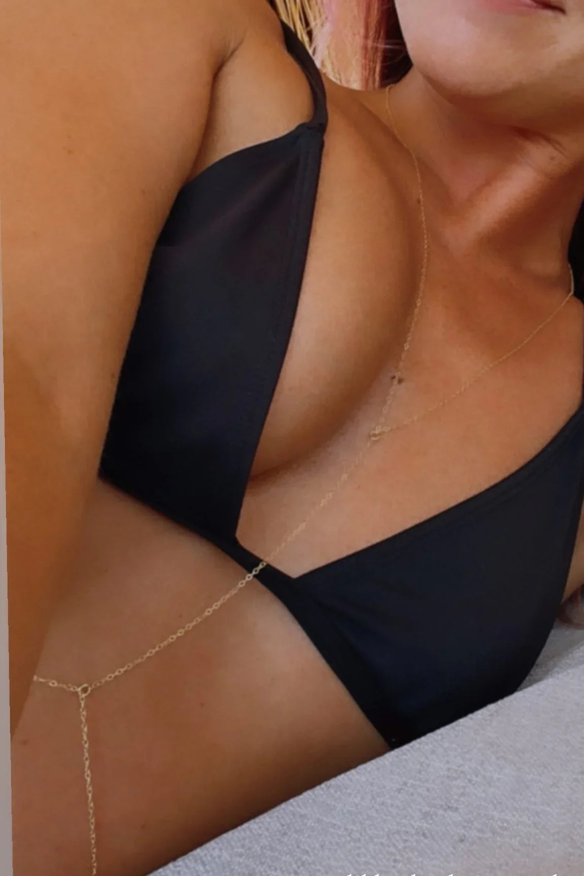 Woman wearing a black bikini top and delicate gold body chain from Love Classic