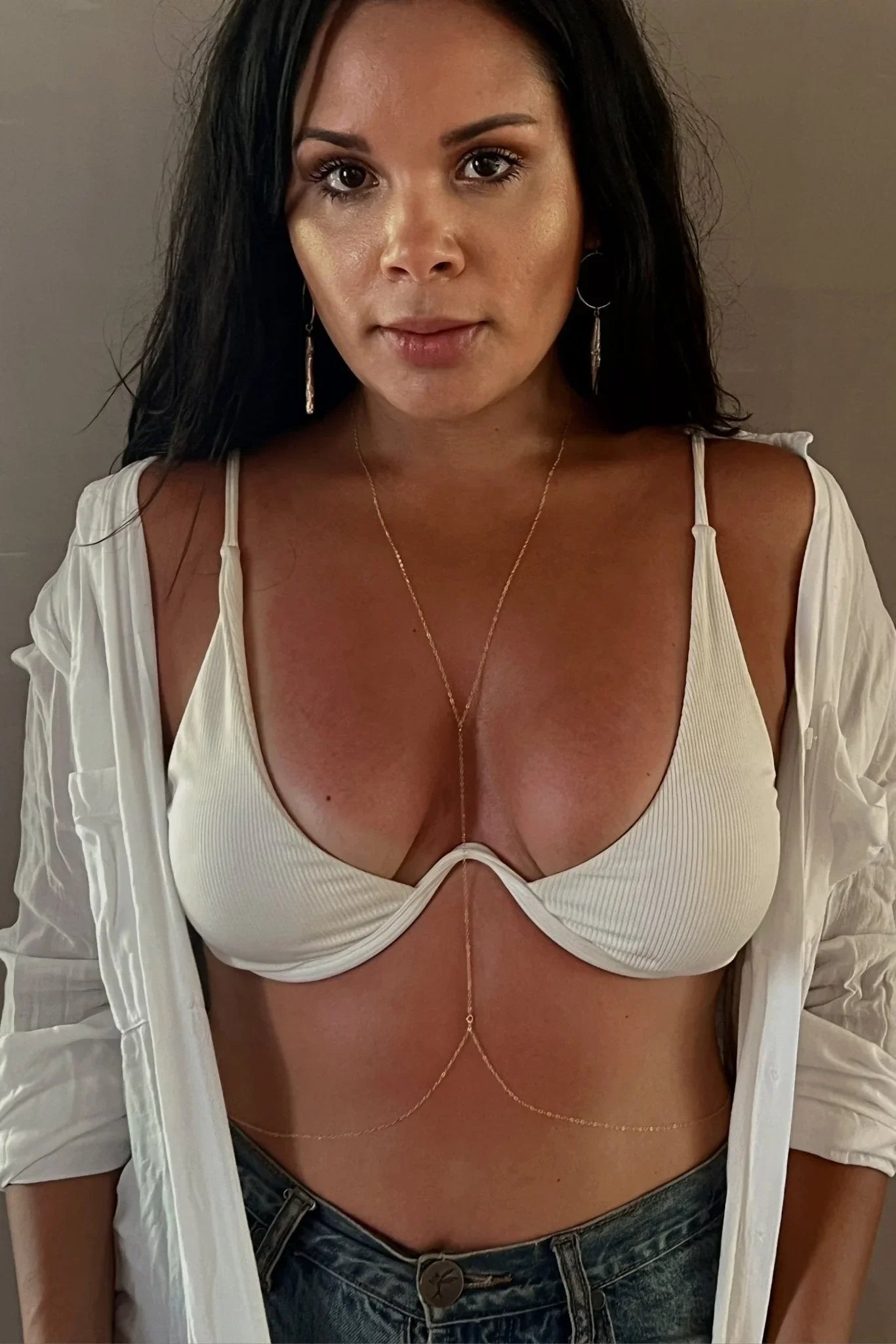 Woman wearing a white bralette, layered body chain, white shirt, and denim for Love Classic style