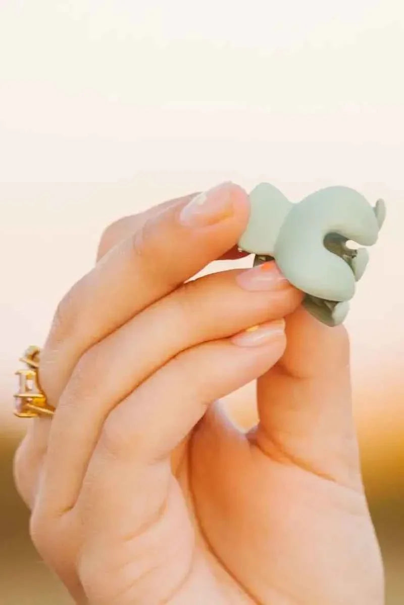 Hand holding small green matte hair claw clip, Love Classic accessory, gold ring visible