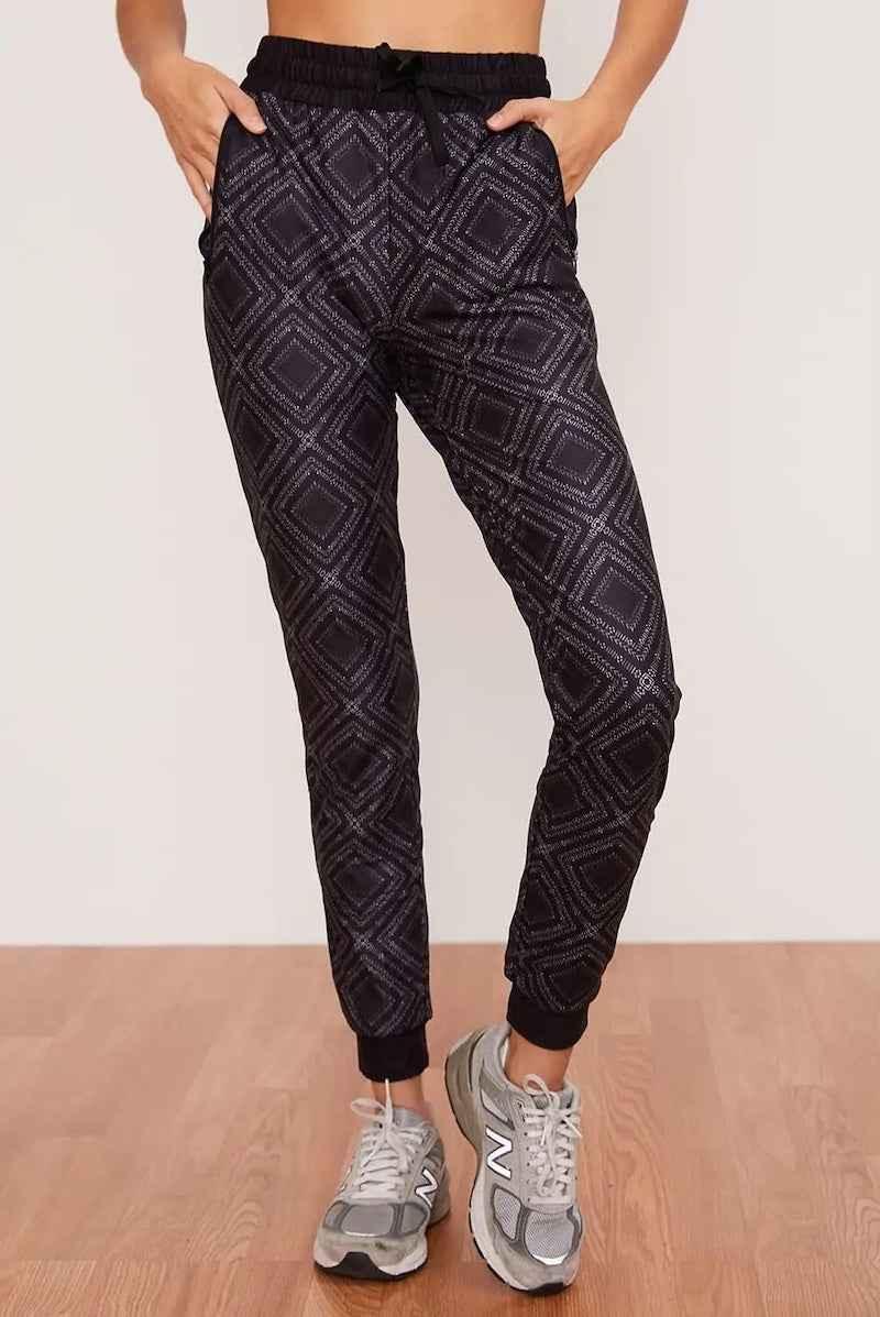 Woman wearing black geometric print jogger pants from Love Classic, casual style on wood floor