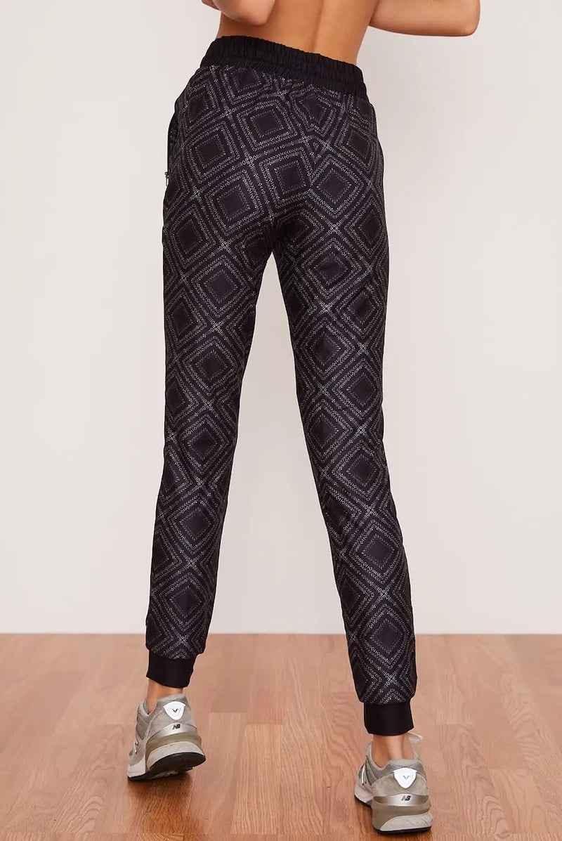 Back view of geometric print jogger pants from Love Classic, shown with sneakers on wood floor