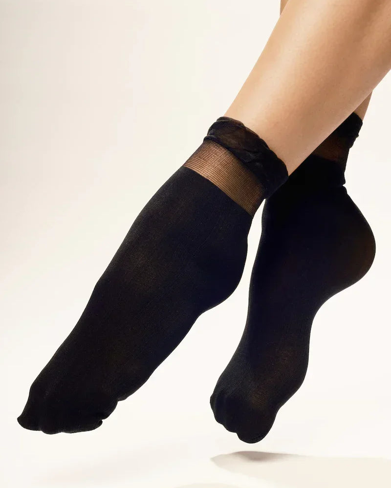 Woman wearing sheer black ankle socks against white background
