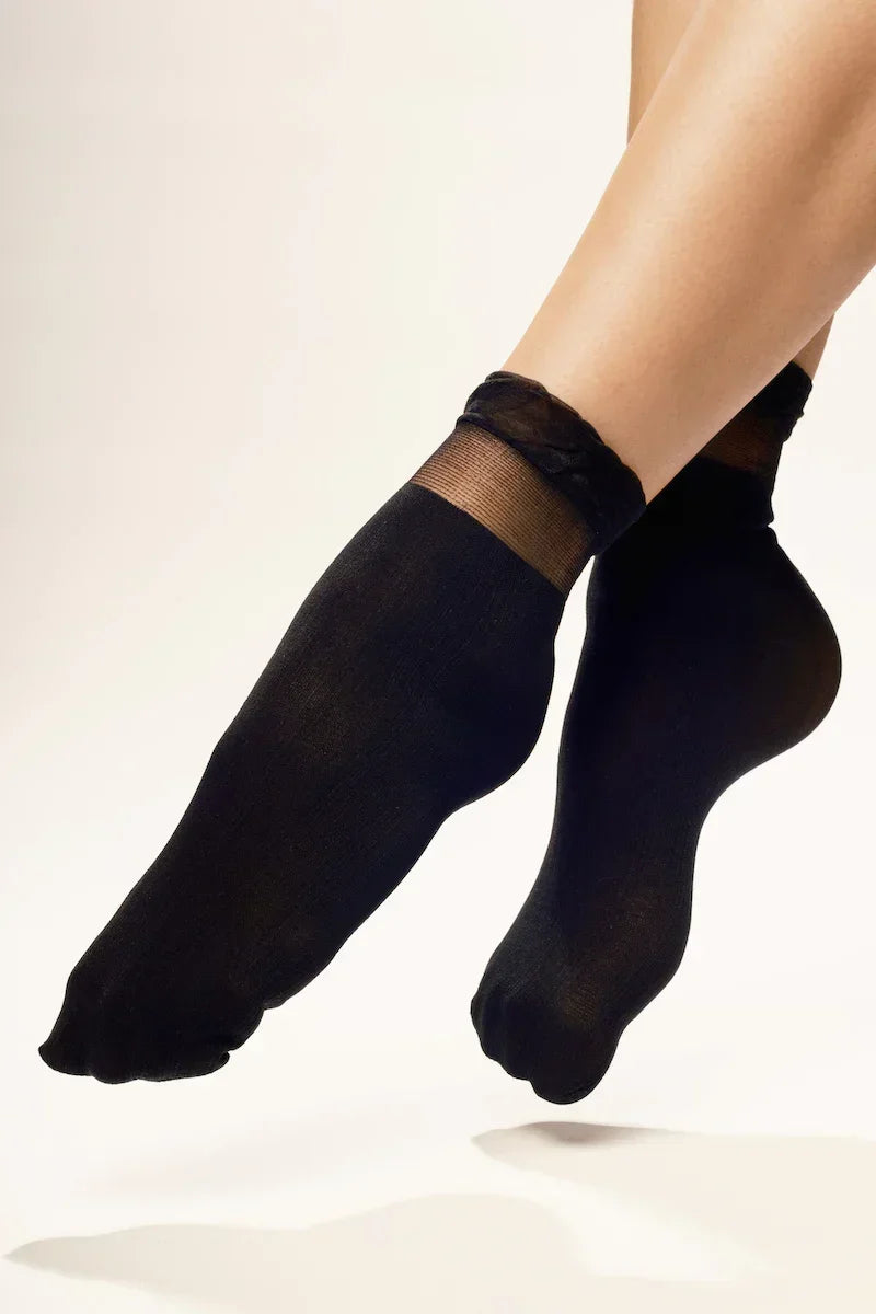 Woman wearing sheer black ankle socks against white background