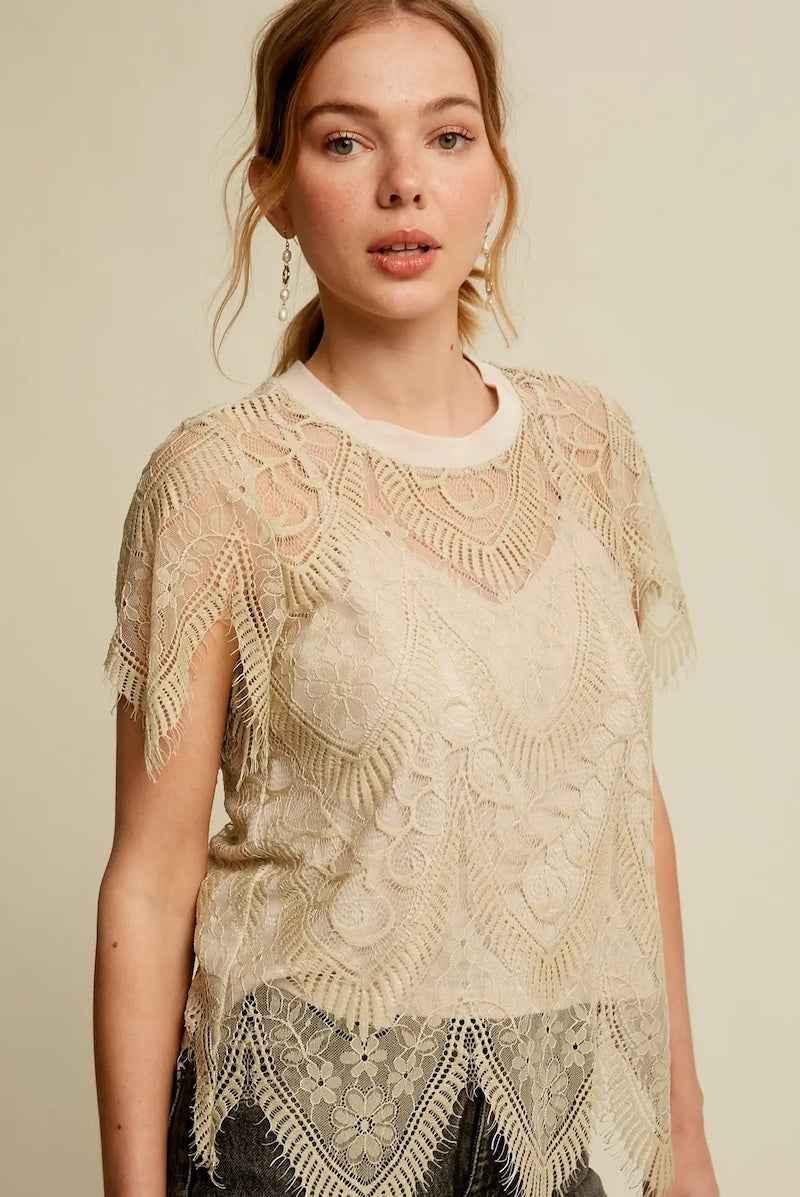 Woman wearing a cream lace blouse with floral patterns from Love Classic fashion collection