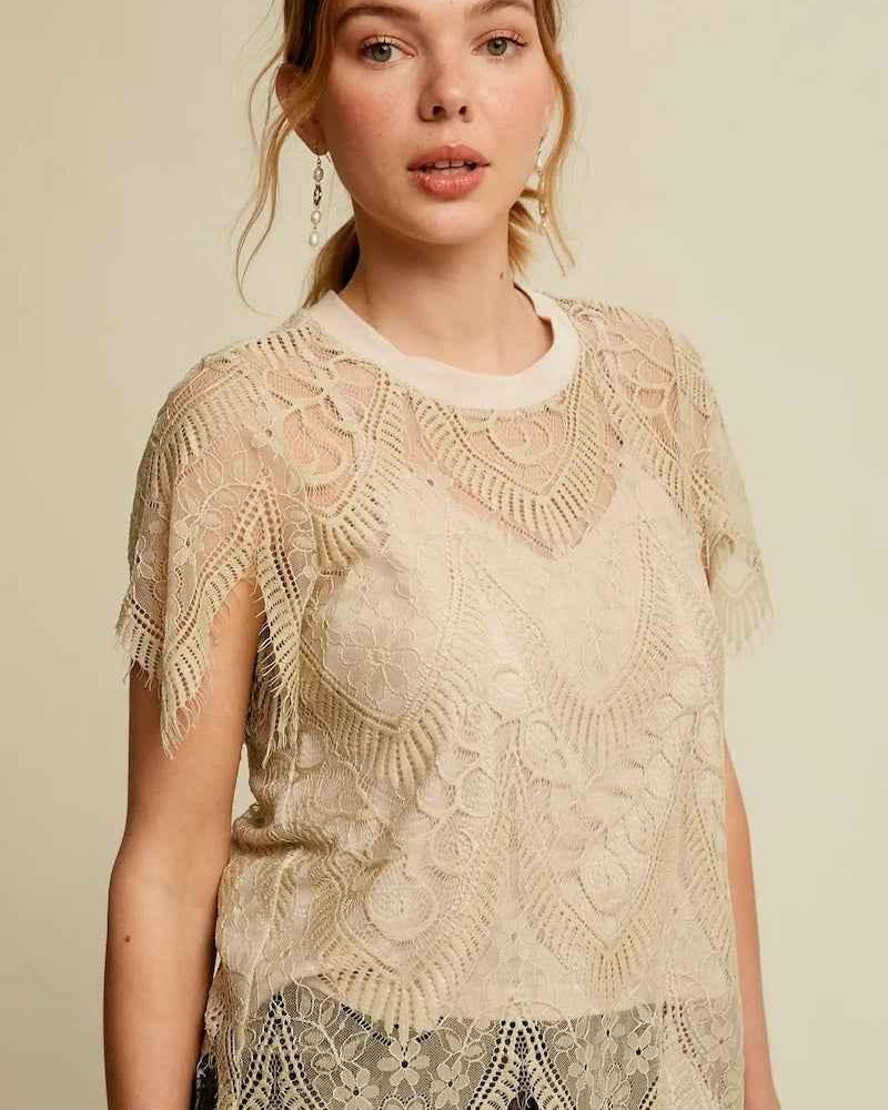 Woman wearing a cream lace blouse with floral patterns from Love Classic fashion collection