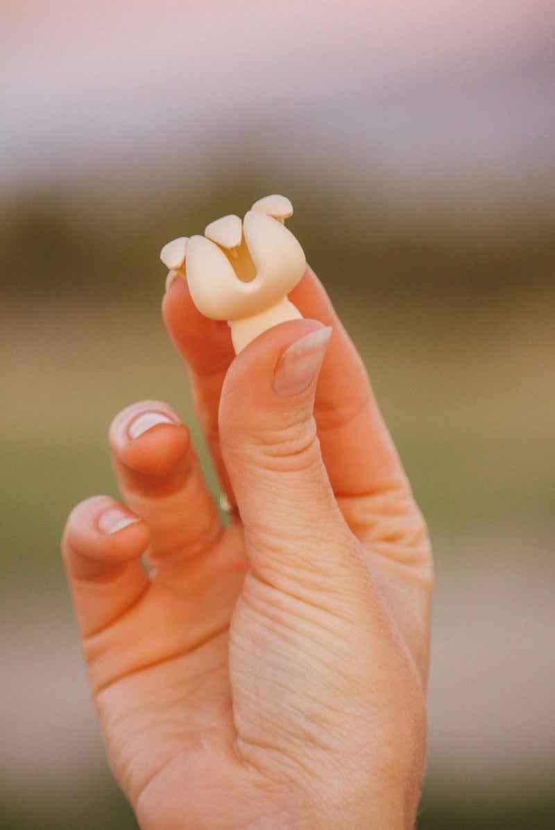 Hand holding a small, unique white accessory outdoors, Love Classic high quality style