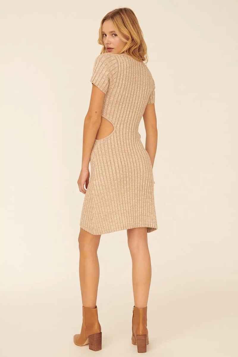 Woman wearing a beige ribbed sweater dress with side cutouts and brown boots from Love Classic