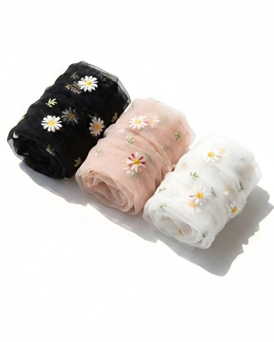 3-pack sheer garden daisy crew socks in black, blush pink, and white, rolled together on a clean white surface to highlight the delicate sheer fabric and embroidered daisy details.
