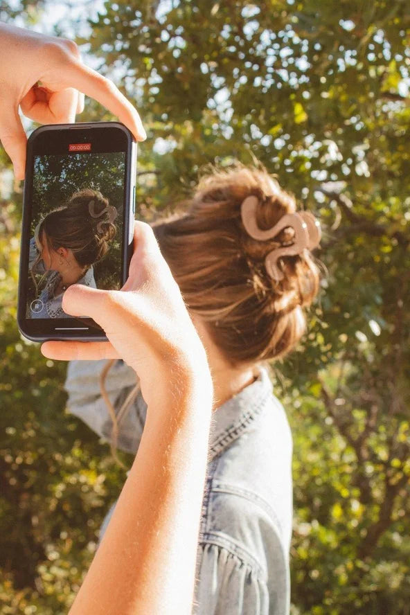 Woman outdoors with hair claw clip styled, photographed on smartphone, Love Classic fashion accessory