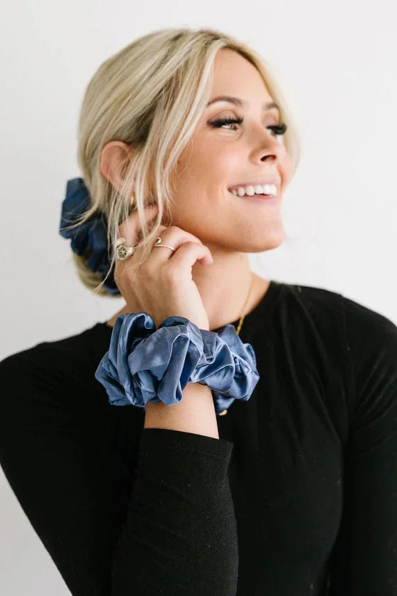 Smiling woman wearing blue satin scrunchies in hair and on wrist, Love Classic style