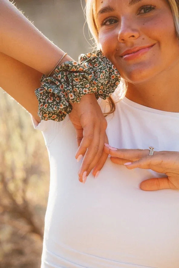 Woman in white shirt wearing floral scrunchie and ring, Love Classic accessory style