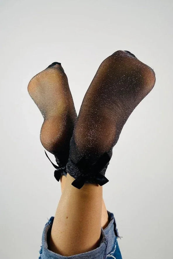 Sheer black glitter socks with bows styled on legs in denim, Love Classic fashion accessory