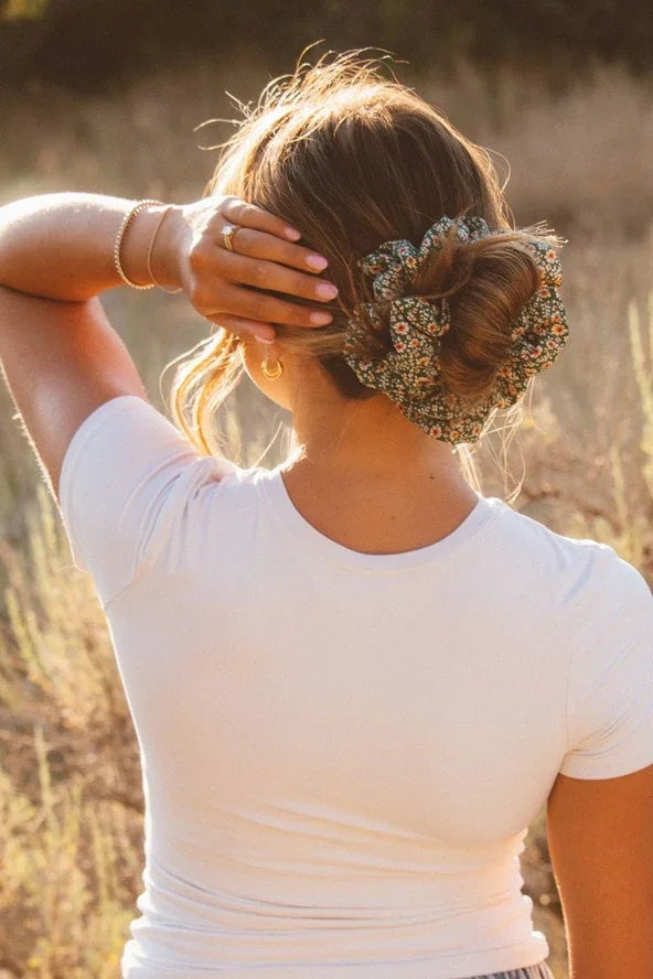 Woman with floral scrunchie in hair wearing white top outdoors, Love Classic fashion style
