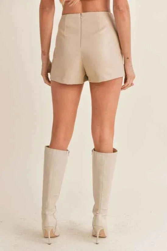 Woman modeling high-waisted beige shorts and knee-high boots, Love Classic fashion style
