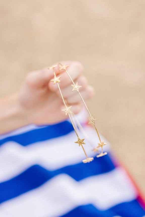 Hand holding gold star headband, striped blue and white background, Love Classic style