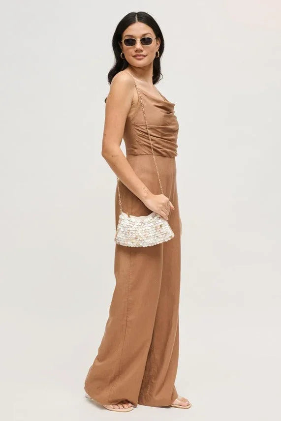 Model holding a compact opalite evening bag that reflects light with an iridescent shine.