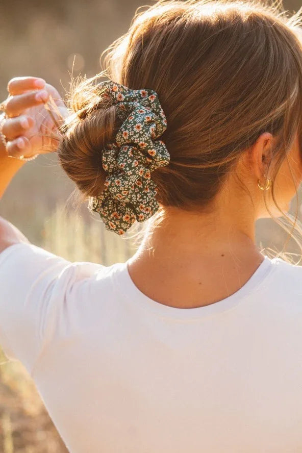 Woman wearing a floral scrunchie in a bun, outdoor sunlight, Love Classic hair accessory style