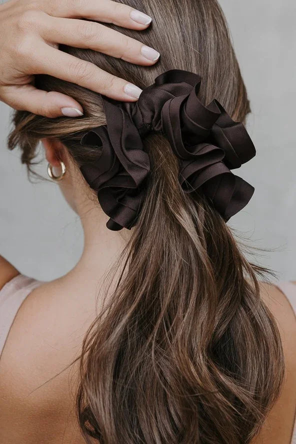 Woman with long brown hair wearing a large dark ruffled scrunchie, Love Classic style.