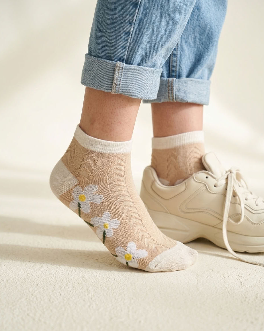 Beige daisy pointelle low-cut socks with cream trim beside a cream sneaker
