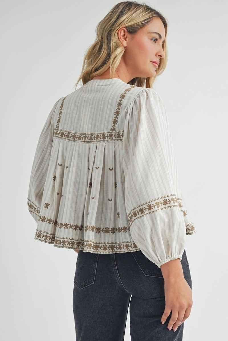 Woman wearing a white boho blouse with floral embroidery, Love Classic fashion style.