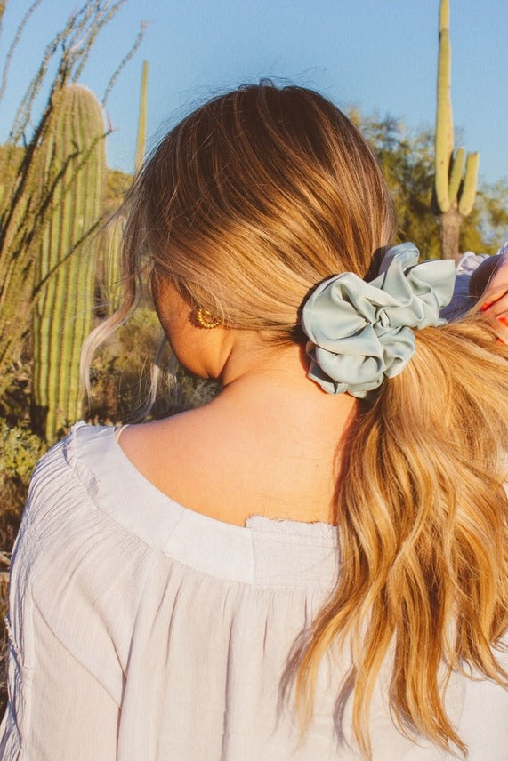 Model shown from the back wearing the Eucalyptus Jumbo Scrunchie featuring matte sateen texture and extra-large design wrapped around a messy bun.