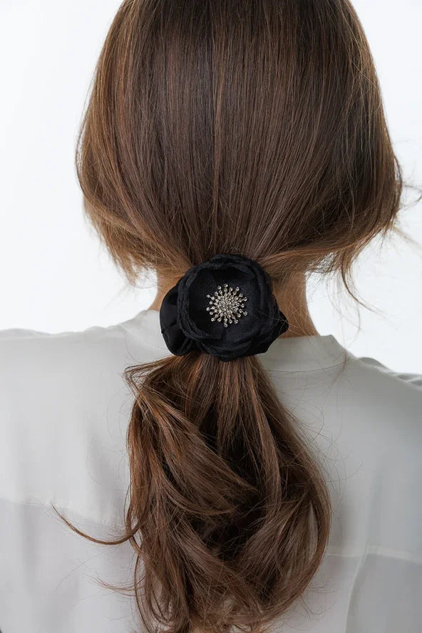 Woman with long brown hair wearing a black floral hair accessory with jeweled center, Love Classic style