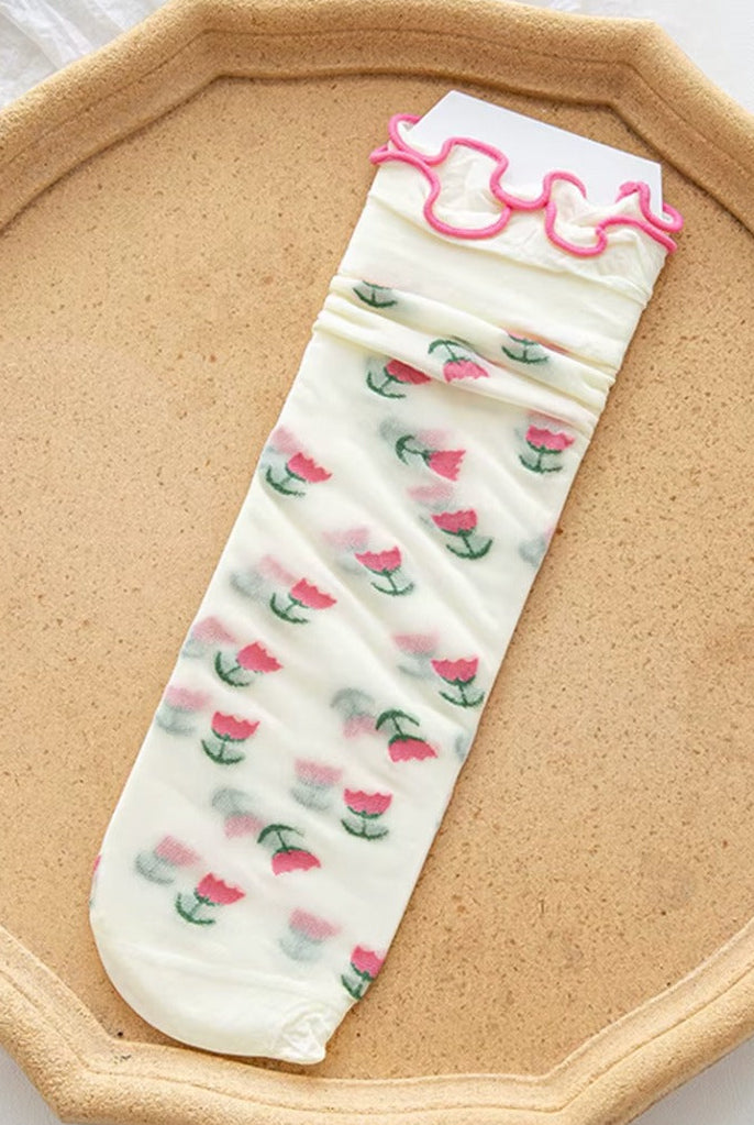 Sheer mesh crew socks with a pink tulips pattern and a soft lettuce-edge cuff on a neutral background.