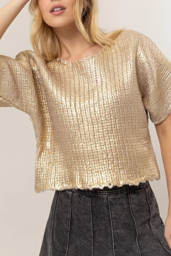 Model wearing the gold Metal Coated Knit Sweater with round neckline, relaxed short sleeves, chunky knit texture, and lettuce-edged hem.