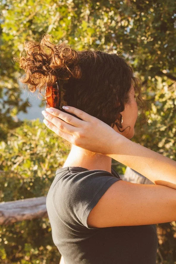 Woman with curly hair in a tortoiseshell clip outdoors, Love Classic casual style