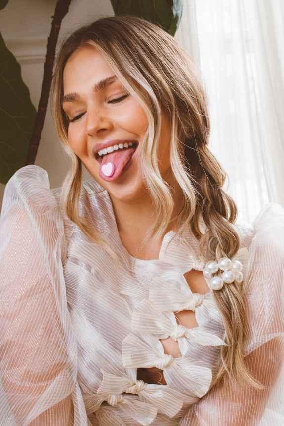 Smiling woman in sheer white top with pearl hair accessory, Love Classic fashion style