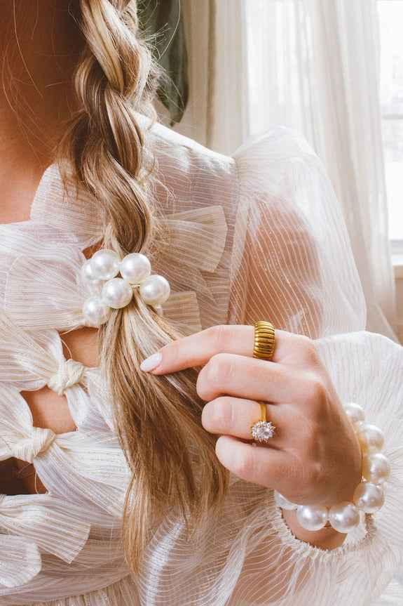 Woman with pearl hair accessory, gold ring, and sheer white blouse from Love Classic