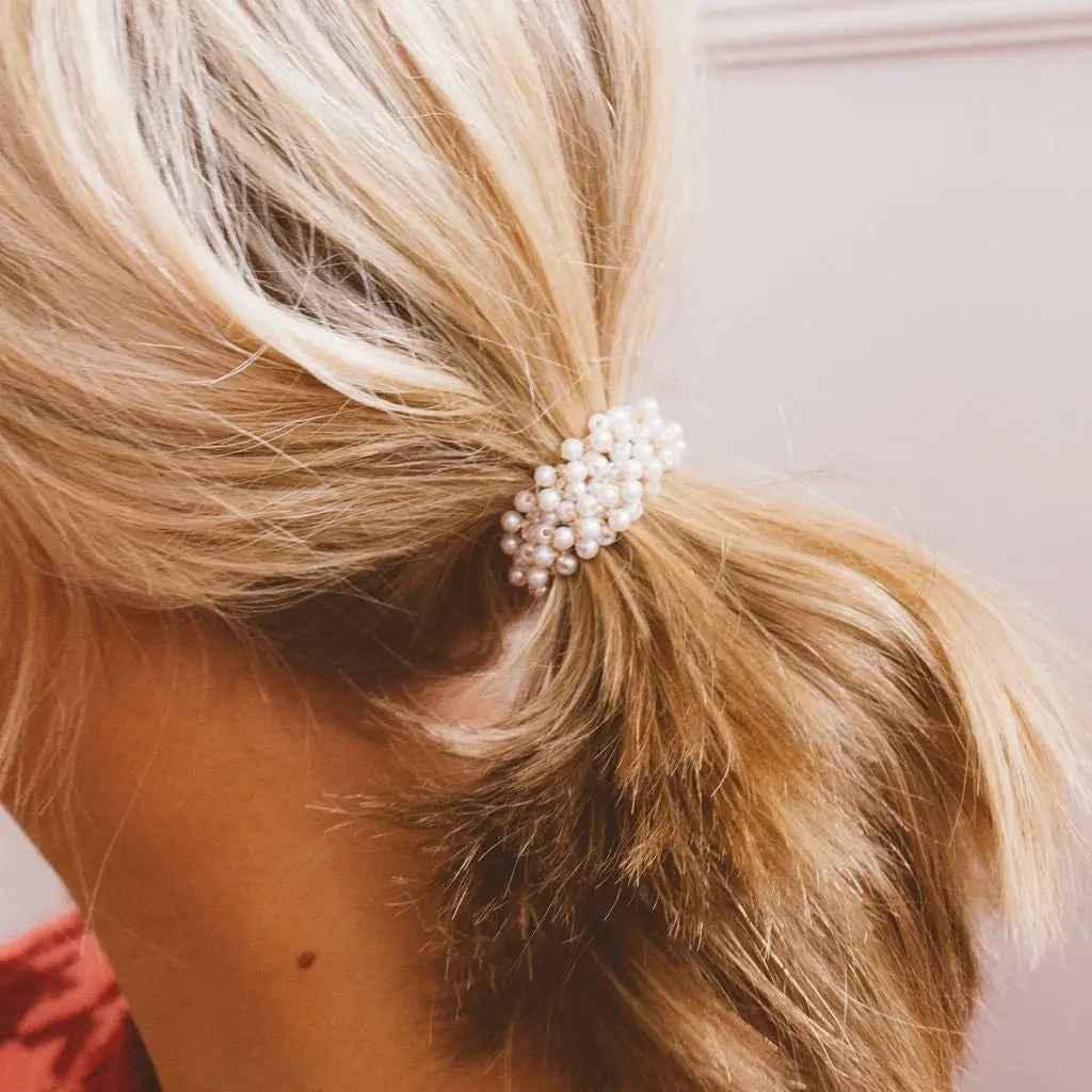 Blonde hair styled in a low ponytail with a pearl hair tie from Love Classic