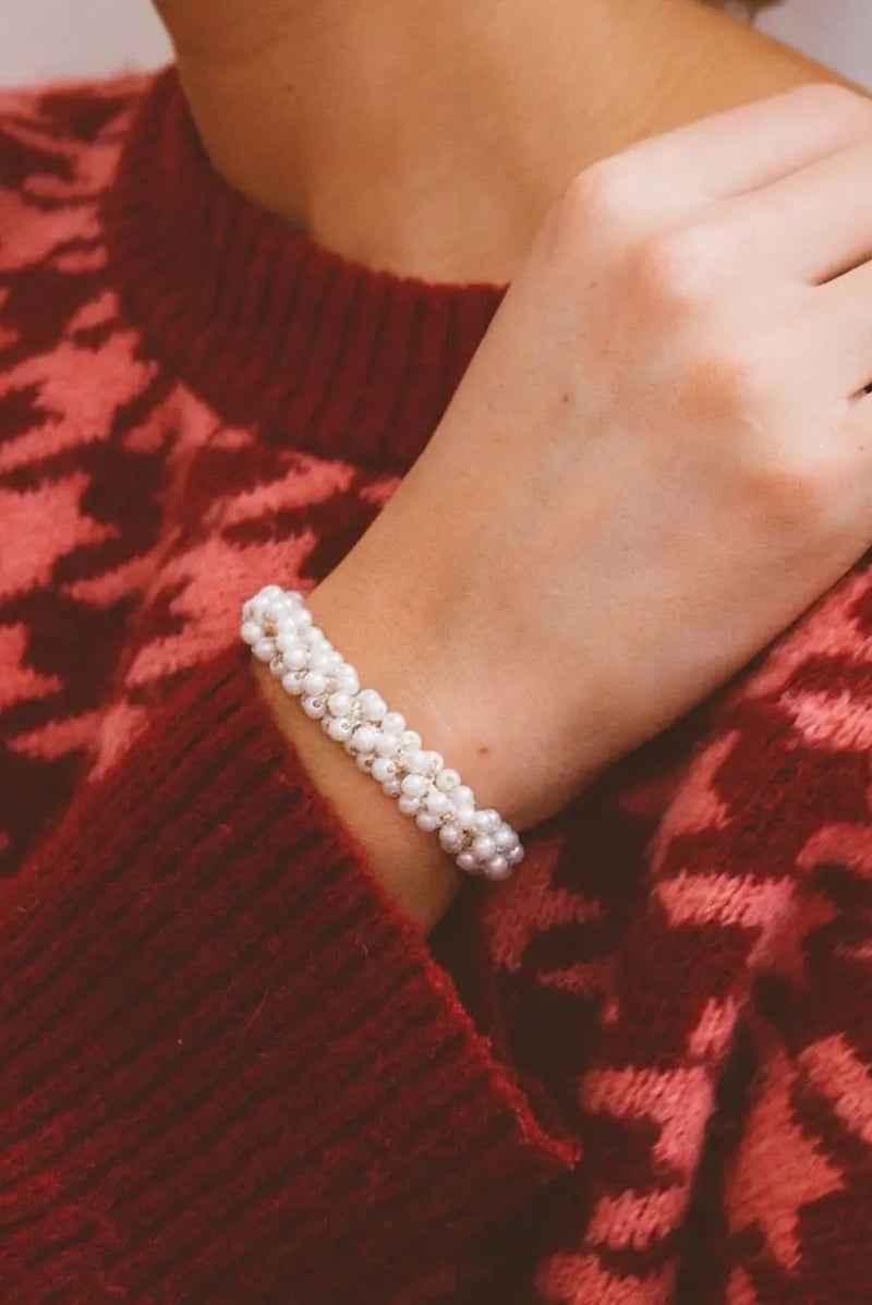 Woman wearing a pearl beaded bracelet and red patterned sweater from Love Classic