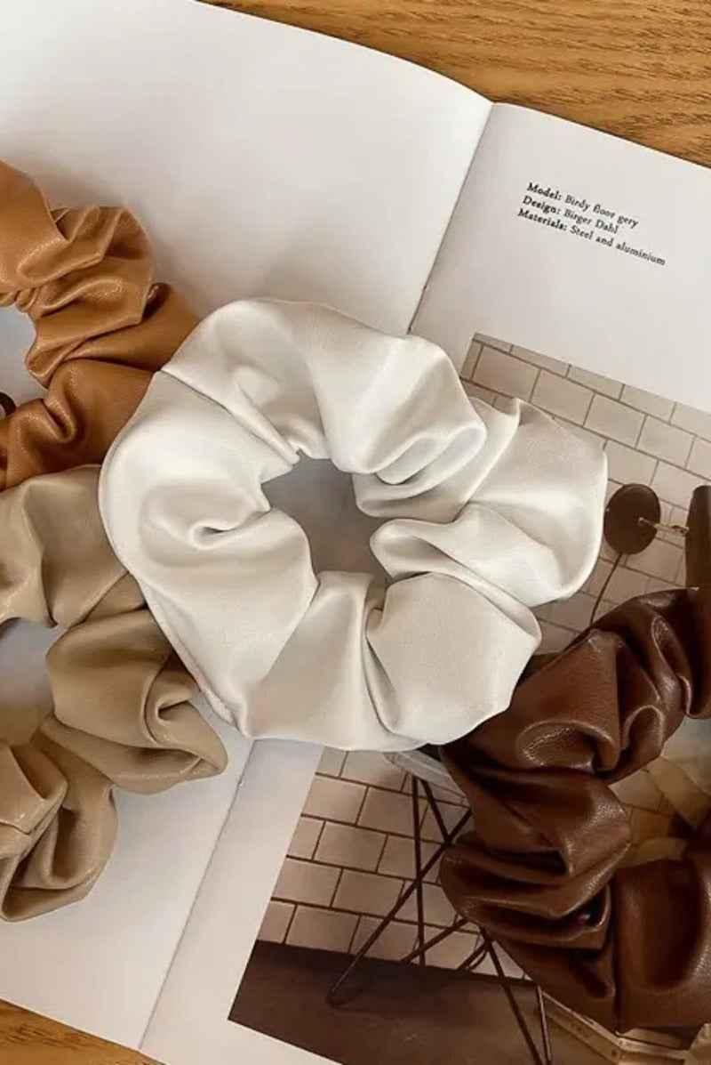 Assorted leather scrunchies in tan, cream, and brown on an open magazine, Love Classic style