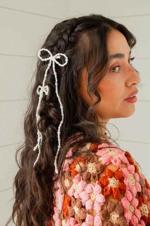 Woman with braided hair wearing pearl bow hair accessory and crochet floral cardigan, Love Classic style