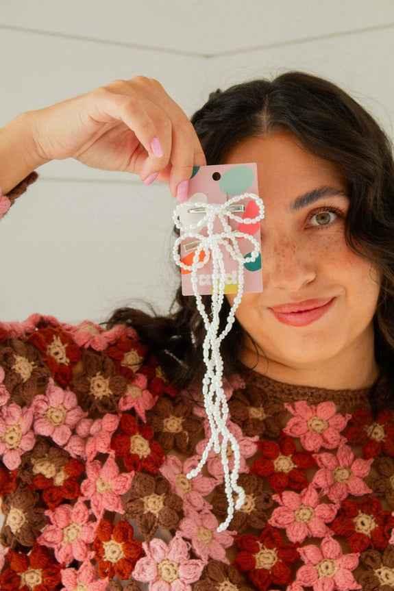 Woman in floral crochet sweater holding Love Classic beaded hair accessory
