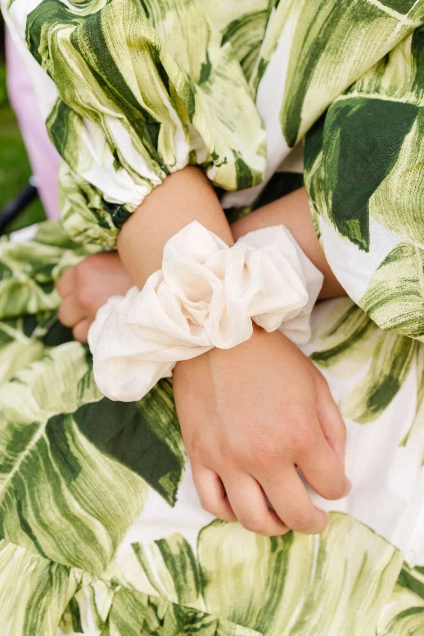 Cream jumbo scrunchie on wrist, person in green leaf print dress, Love Classic accessory