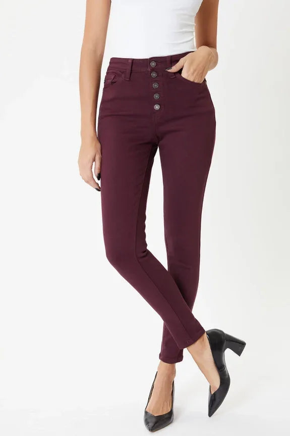 Woman wearing burgundy high-waisted skinny jeans, white tank top, and black heels
