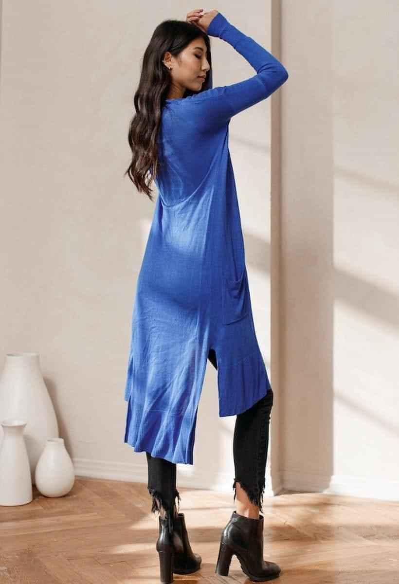 Woman wearing a long blue cardigan from Love Classic, styled with black jeans and boots