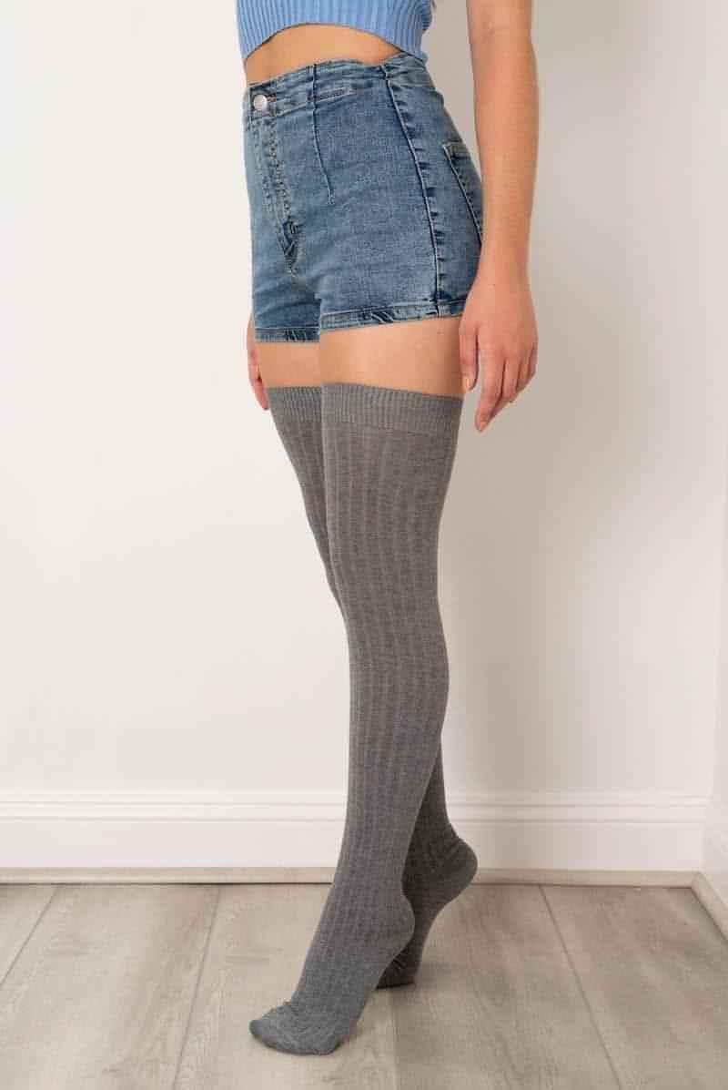 Woman wearing gray over the knee socks, denim shorts, and a blue crop top; Love Classic style