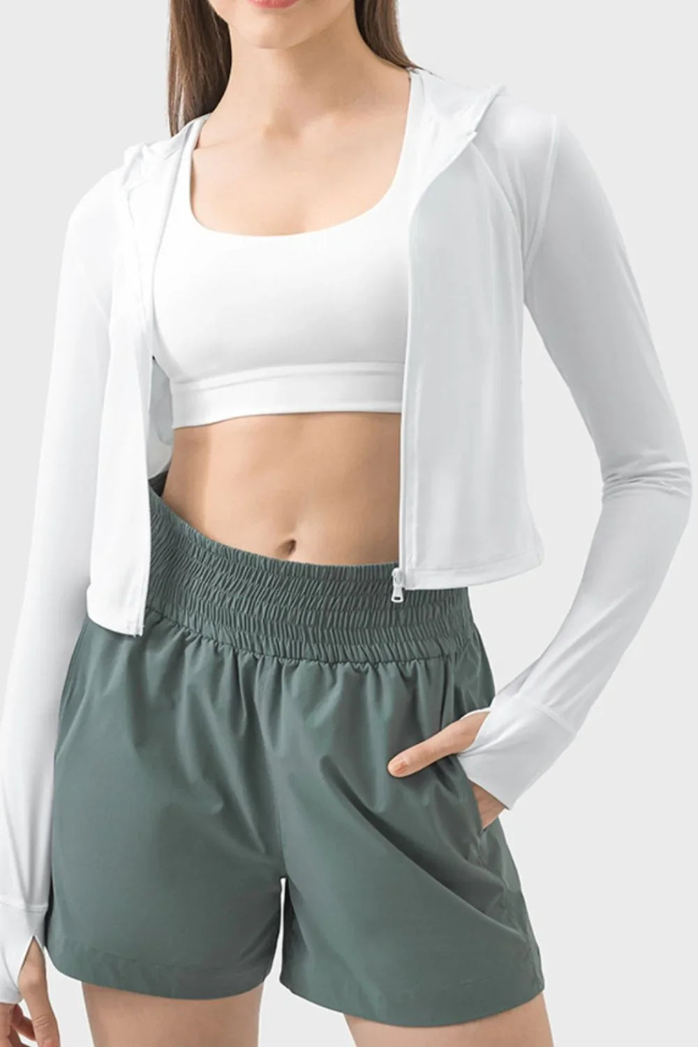 Woman in white zip hoodie and sports bra with green shorts, Love Classic activewear