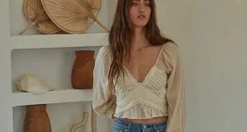 Woman in cream boho blouse and jeans, Love Classic style, standing by decorative vases.