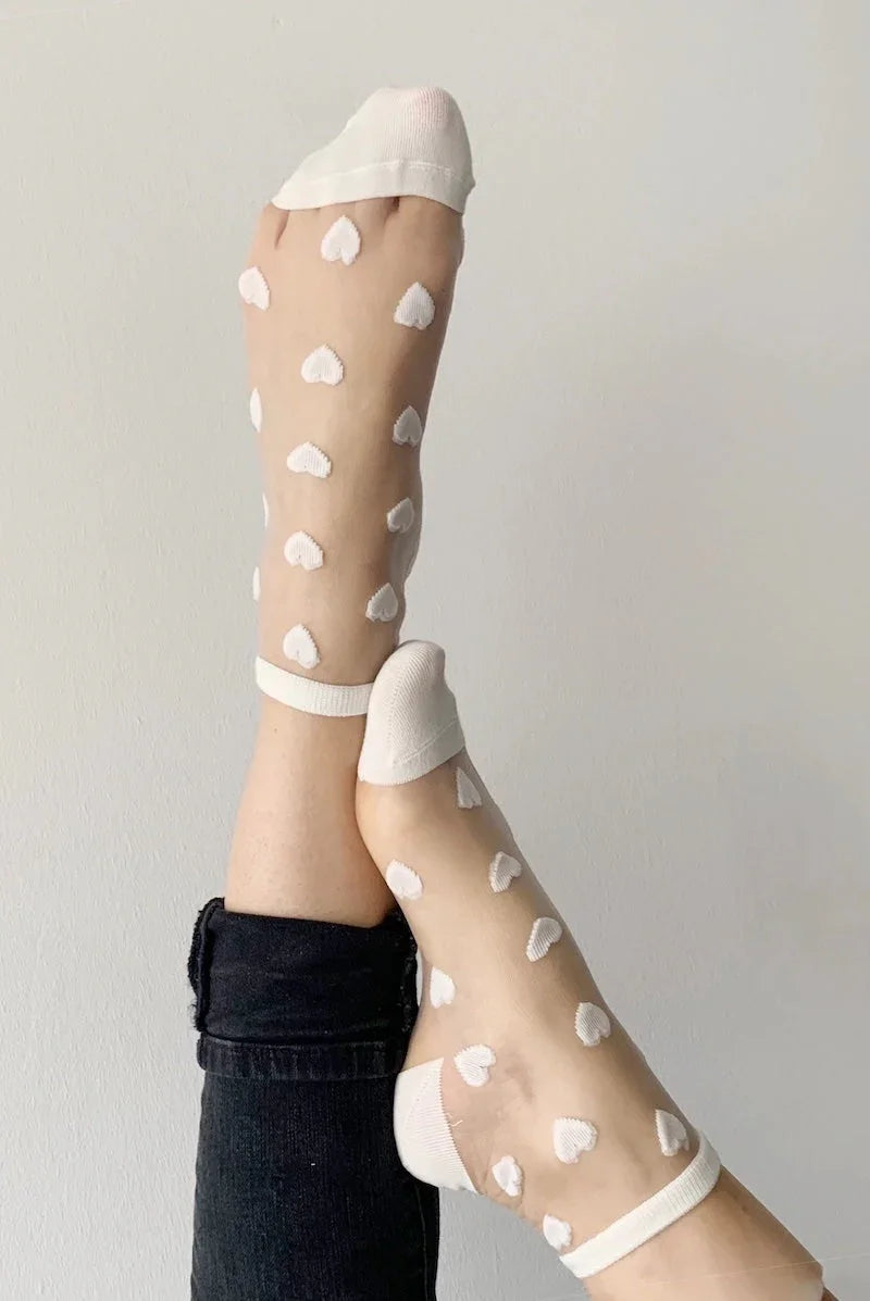 Sheer white socks with heart patterns from Love Classic, worn with black jeans