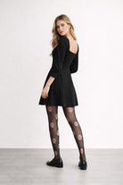 Sheer black floral tights with rose pattern styled with a black mini dress and loafers 2