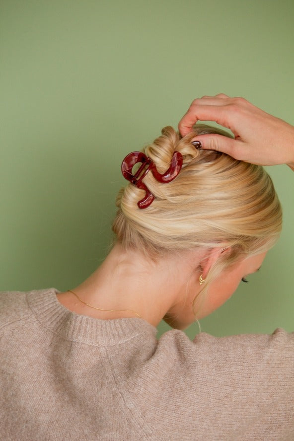 Model holding hair up with Swirl Claw Clip, showcasing the stunning design and perfect color for the season.
